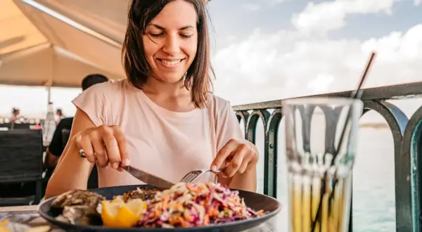 Frau genießt Fisch mit Salat, eine Mahlzeit, die gut zur pescetarier bedeutung passt.