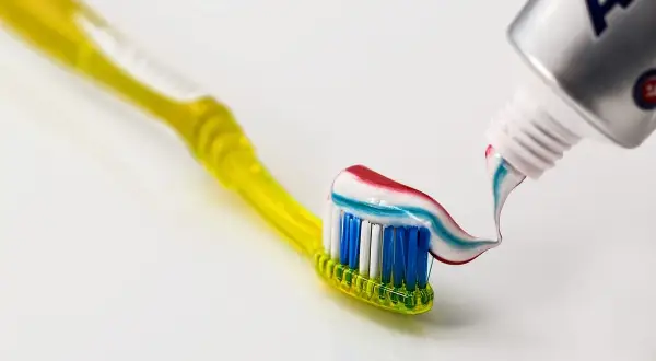 Szczoteczka z kolorową pastą, na której widać strumień z tubki. Czy fluor jest szkodliwy? Debata trwa, ale pasta z fluorem chroni zęby.
