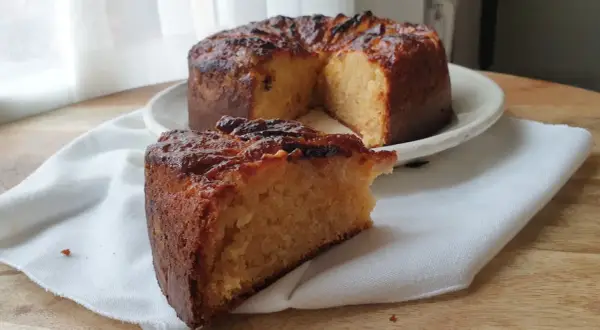 Un delicioso bizcocho de plátano y manzana, con una rebanada servida sobre una servilleta blanca.