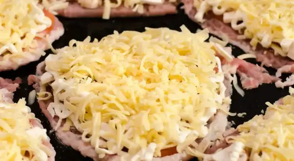 Schab w plastrach pieczony w piekarniku z pieczarkami i serem, gotowy do zapieczenia.