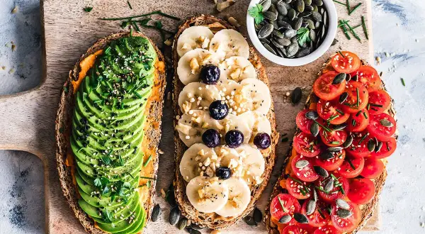 Trois toasts variés : avocat, banane-myrtille, tomates. Une alimentation riche en protéines pour bien commencer la journée.