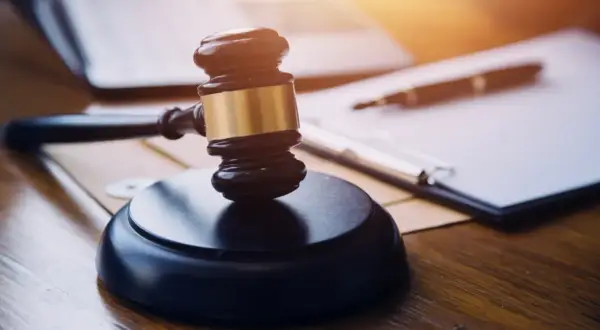 Młotek sędziowski na biurku, obok dokumentów i długopisu. Symbol sprawiedliwości i prawa, jak w art. 130 1a kpc.