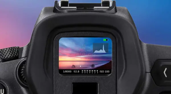 Il mirino elettronico mostra un tramonto mozzafiato sul mare, con impostazioni di scatto e istogramma.