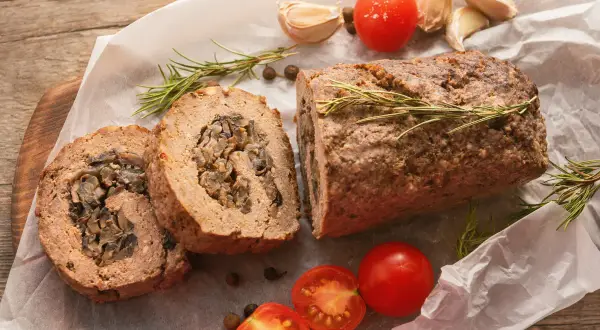 Pyszna rolada z mięsa mielonego z grzybami, podana z pomidorkami i rozmarynem.