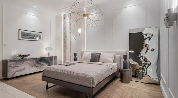 Nowoczesna sypialnia z łóżkiem, marmurową komodą i designerskim lustrem. Inspiracja, jak urządzić sypialnię w eleganckim stylu.