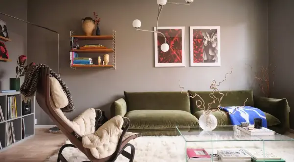 Salotto moderno con divano verde, poltrona in pelle e tessuto chiaro, tappeto bianco soffice e quadri alle pareti che creano un gioco di **colori chiari e scuri**.