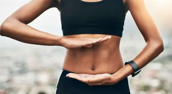 Femme pratiquant des exercices abdo hypopressifs, mains posées sur son ventre plat.
