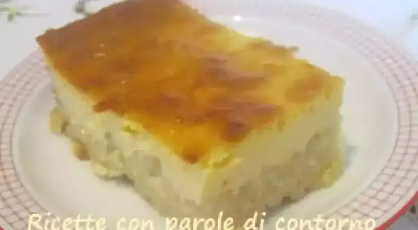Una fetta di torta di riso carrarina, con una base soffice e una crema dorata in superficie, servita su un piatto a scacchi.