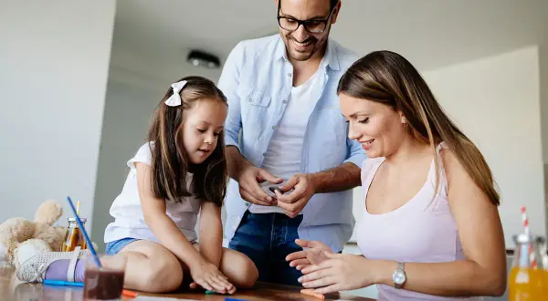 Familia feliz disfrutando de una **actividad día de la familia**, creando arte con plastilina y colores.