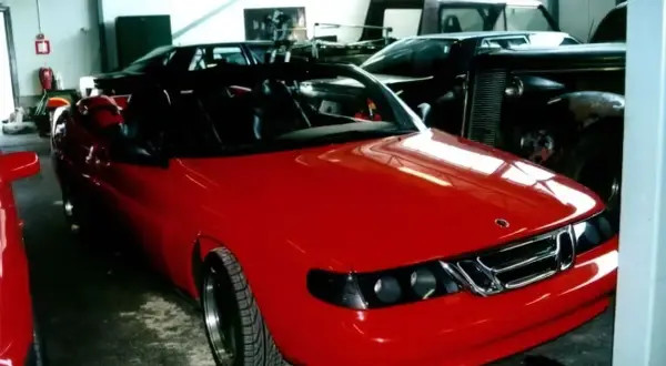 En röd Saab 9000 cabriolet står i ett garage, redo för en tur.