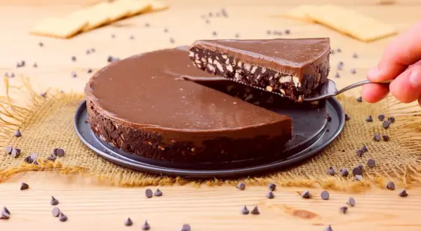 Torta al cioccolato con biscotti, un'idea per dolci velocissimi senza cottura. Una fetta viene sollevata con una paletta.