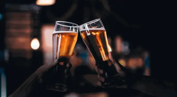 Due mani brindano con due bicchieri di birra dorata, un gesto che nasconde un'intolleranza alla birra.