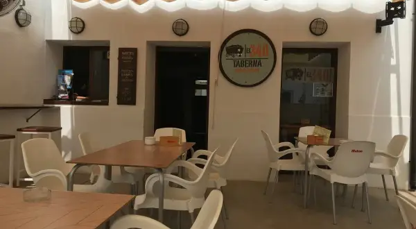 Terraza del restaurante 340, con mesas y sillas de plástico blanco bajo un toldo beige.