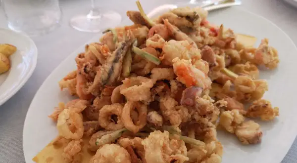 Un piatto invitante di frittura di paranza, con calamari, gamberi e pesciolini dorati e croccanti.