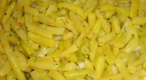 Nahaufnahme von gekochten gelben Bohnen, gewürzt mit Kräutern und Zwiebeln. Ein leckeres Gericht mit gelben Bohnen.