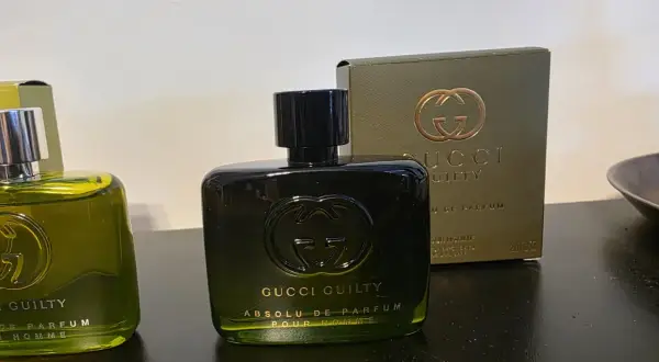 Dwie butelki perfum Gucci Guilty na ciemnym tle, jedna z nich z pudełkiem.