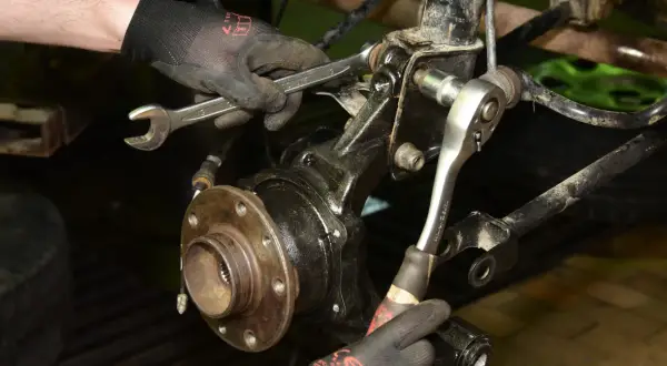 Mechanik dokręca śruby przy piaście, gdzie znajduje się łożysko w kole.