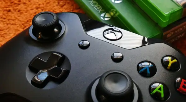 Czarny kontroler Xbox i zielone pudełka z grami. Idealny zestaw do wspólnej zabawy w gry survival multiplayer.