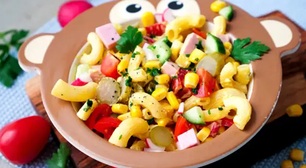 Bunter Nudelsalat mit Mais, Tomaten und Gurken in einem Affen-Teller – perfekt für Kinder!