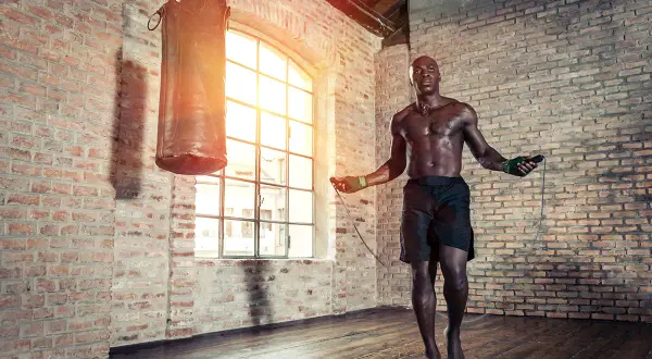 A boxer jumps rope in a brick gym. Jump rope is good for boxing because it builds stamina, agility, and footwork.