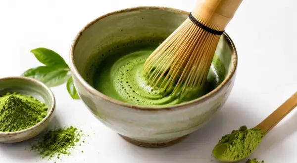 Przygotowanie idealnego naparu matcha: zielony proszek, bambusowa miotełka i miseczka z pianką.