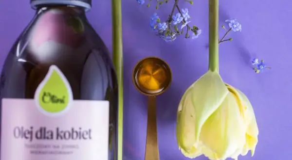 Olej dla kobiet i kwiaty symbolizują naturalne sposoby na menopauzę. Złota łyżeczka z płynem sugeruje wsparcie w tym okresie.