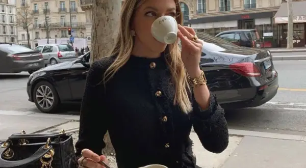 Elegancka kobieta w czarnym tweedowym żakiecie, uosobienie stylu moda quiet luxury, popija kawę w paryskiej kawiarni.