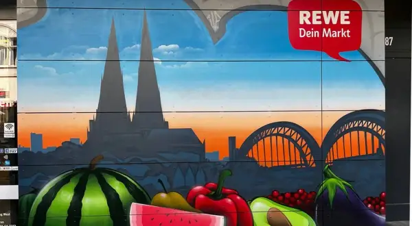 Graffiti mit Kölner Dom, Brücke und Früchten vor REWE-Logo.