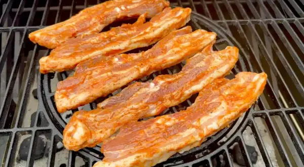 Paski boczku w aromatycznej marynacie do boczku pieką się na grillu.