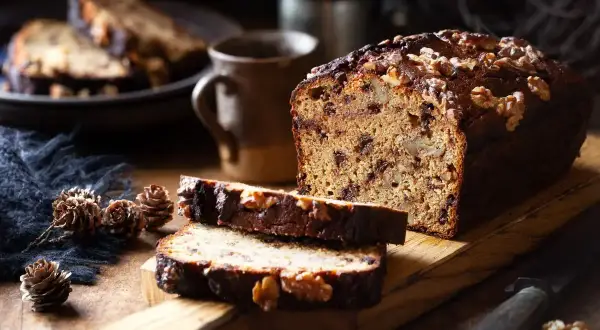 Plumcake noci e cioccolato, con fette tagliate e noci intere sparse. Un'atmosfera rustica e invitante.