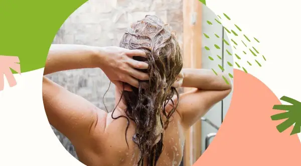 Kobieta masuje mokre włosy pod prysznicem, stosując naturalny peeling do skóry głowy.