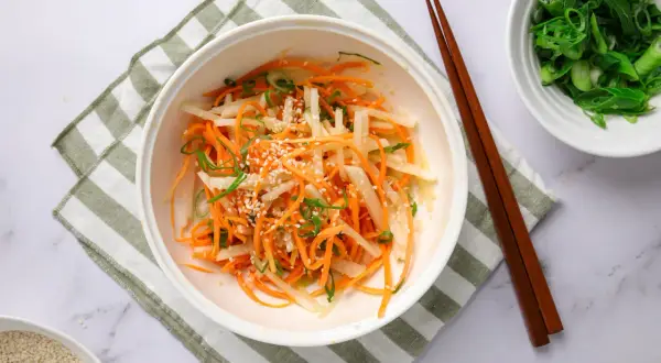 En fräsch sallad med strimlad daikon, morot och salladslök, toppad med sesamfrön. Ett enkelt daikon recept.