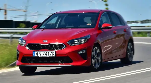 Czerwony Kia Ceed 1.4 benzyna w ruchu drogowym. Elegancki design i dynamiczna jazda.
