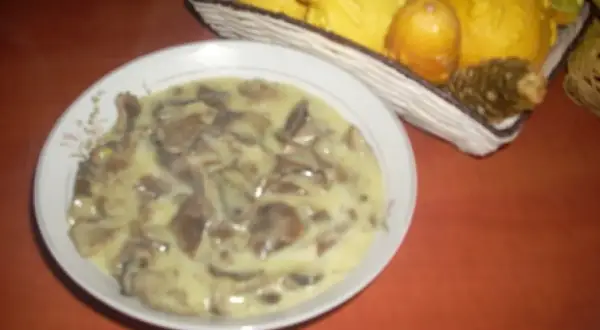Talerz z kremowym sosem grzybowym, w tle koszyk z ozdobnymi dyniami.