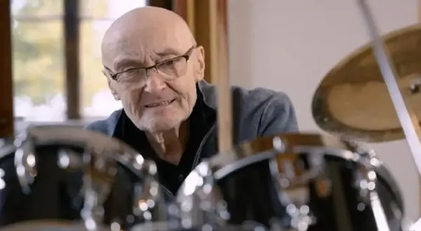 Phil Collins, legenda perkusji, siedzi przy zestawie bębnów, gotów do gry.