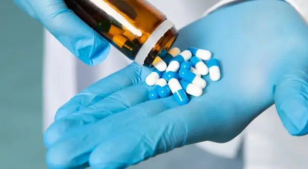Rękawiczki chirurgiczne i buteleczka z lekami. W stomatologii antybiotyki są często przepisywane, aby zapobiegać infekcjom.