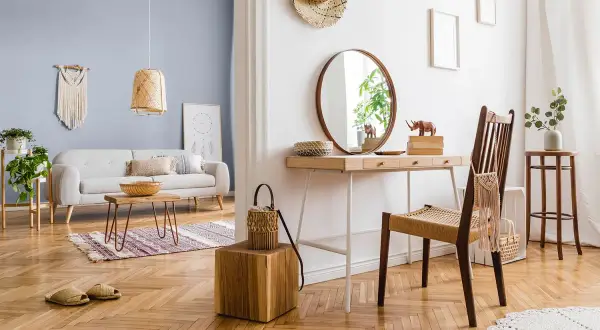 Jasny salon z sofą i stolikiem kawowym. Obok toaletka z lustrem i krzesłem. Jaki kolor pasuje do białego? Jasne drewno i pastelowy błękit tworzą przytulną atmosferę.