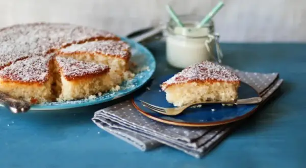 Deliziosa torta con farina di cocco, spolverata di zucchero a velo, servita su piatti blu.