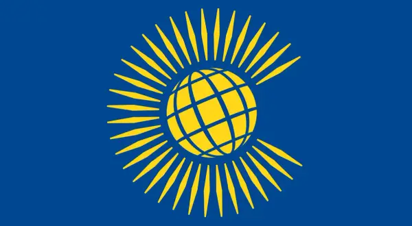 Bandera azul con un globo terráqueo amarillo rodeado de rayos amarillos, representando el Commonwealth.