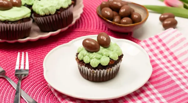 Schokoladen-Oster-Cupcakes mit hellgrüner Glasur und Schokoladen-Eiern, bereit zum Genießen.