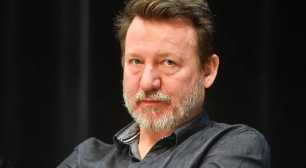 Robert Więckiewicz, znany z wielu filmów, seriali i programów, patrzy prosto w obiektyw.