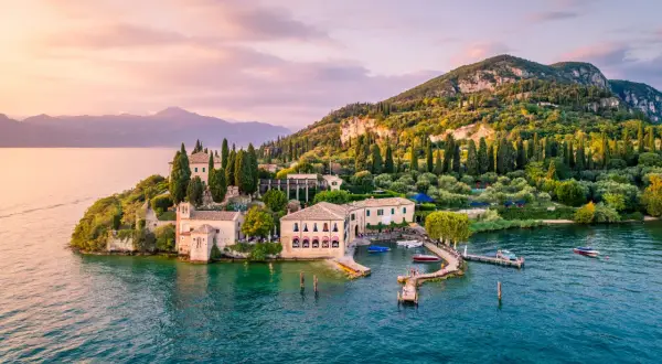 Un'isola incantevole sul gardasee westufer, con ville storiche, cipressi e ulivi, bagnata da acque turchesi al tramonto.