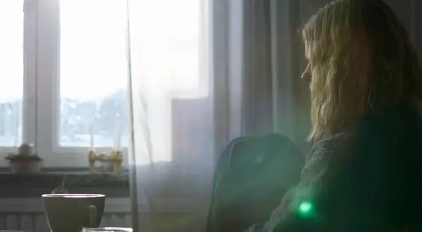 En person sitter ensam vid ett fönster med en kopp kaffe. Kanske en stund av reflektion kring att sluta dricka alkohol och hantera depression.