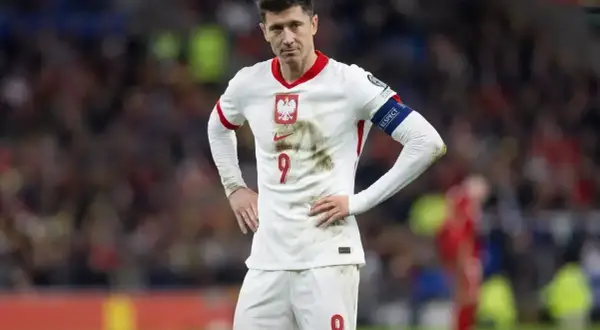 Robert Lewandowski w białej koszulce reprezentacji Polski, z numerem 9 na piersi i spodenkach.