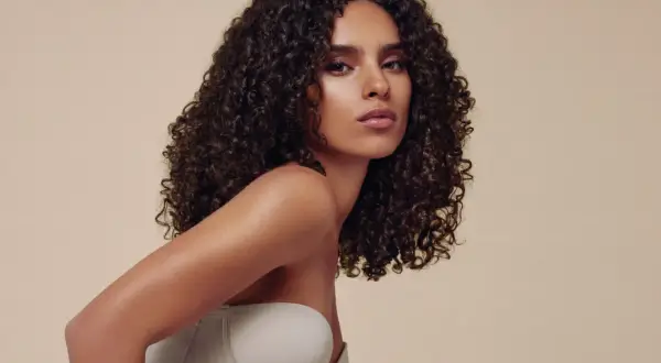 Descubre cómo peinar pelo rizado con esta modelo de cabello oscuro y voluminoso. Su melena luce definida y brillante, perfecta para cualquier ocasión.