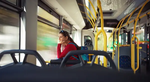 Kobieta w czerwonej bluzce podróżuje autobusem, zastanawiając się, czy Bułgaria jest bezpieczna.