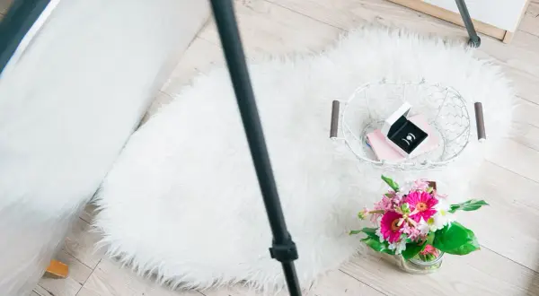 Zdjęcia flat lay: białe futrzane dywaniki, koszyk z biżuterią i bukiet kwiatów.