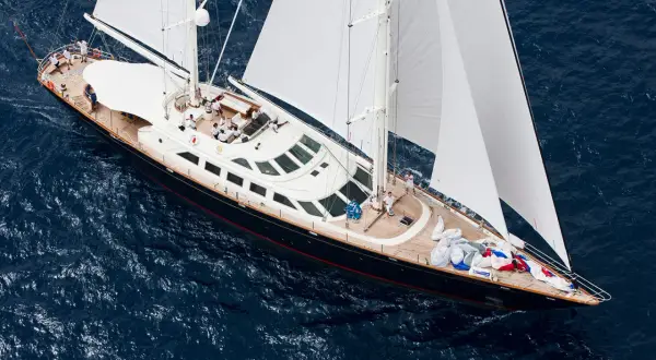 Lussuoso yacht a vela, forse il yacht Berlusconi, solca le acque blu con vele bianche spiegate.