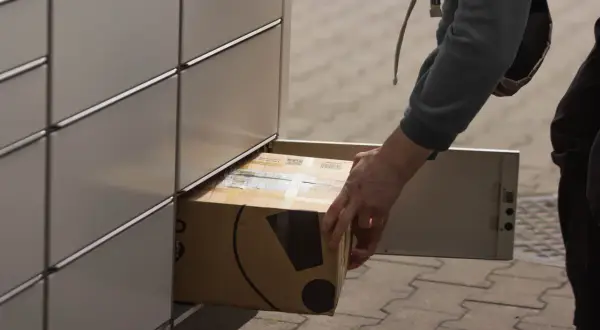 Osoba wkłada paczkę do paczkomatu InPost.