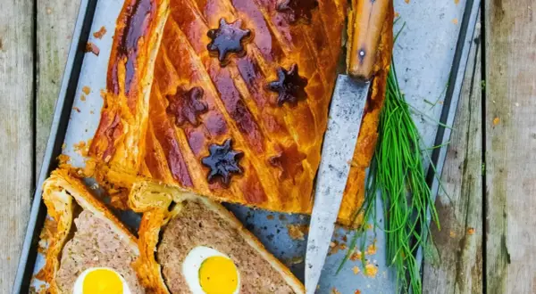 Pâté de Pâques doré, décoré d'étoiles, avec des œufs entiers au cœur. Une recette festive prête à être dégustée.